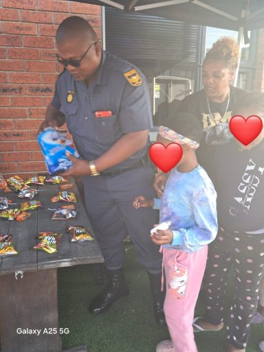 A police officer distributes snacks to children at an outdoor community event.