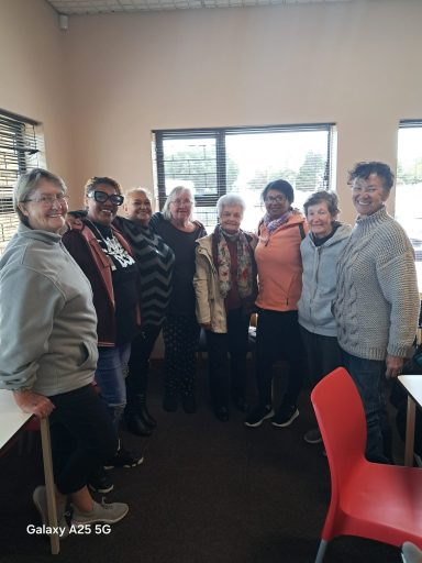 A group of eight people smiling together in a bright indoor setting.
