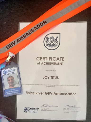 Certificate of achievement for Joy Titus, accompanied by an ID badge and orange ambassador ribbon.